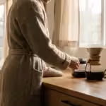 A person pouring freshly brewed coffee in a sunlit modern kitchen with a smart plug visible.